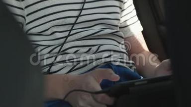 开车时带着耳机玩平板电脑和智能手机的男孩
